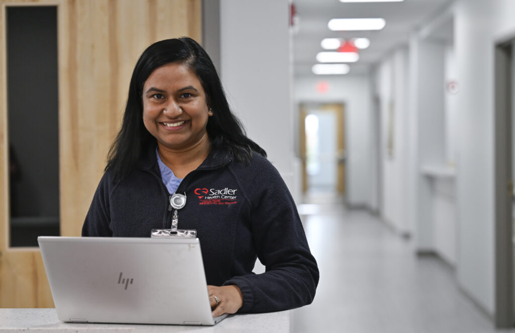 A female Sadler employee smiling behind her laptop.